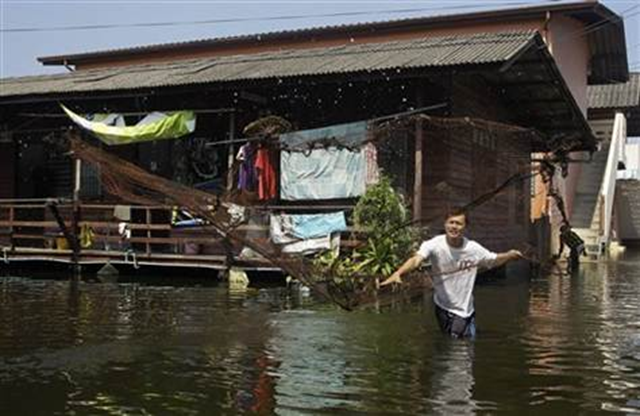 A Thai resident throws his net to catch fish at a floods area in Phisi Charoen district in Bangkok, Thailand, Saturday, 12 November 2011. Thailand's Prime Minister Yingluck Shinawatra has struck a note of partial optimism over the floods plaguing her country, saying that if the water penetrates into the capital's central districts, it will not be too deep. Sakchai Lalit  /  AP