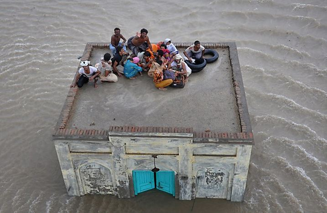 Surrounded by floodwaters, victims of the Pakistan floods await rescue on the roof of a building. justforeignpolicy.org