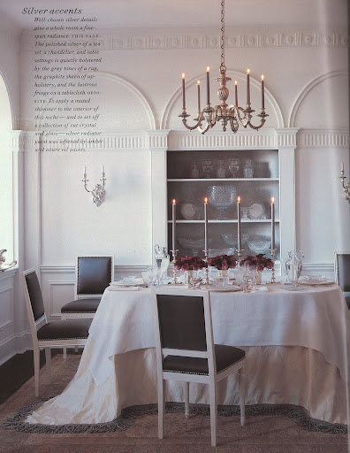 The polished silver of a tea set, a chandelier, and table settings is quietly bolstered by the gray tones of a rug, the graphite sheen of upholstery, and the lustrous fringe on a tablecloth.
