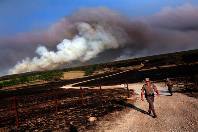Texas State Troopers Aaron Lewis and Greg Sullivan open a gate to allow livestock to escape a running wildfire on April 19, 2011 in Graford, Texas. Getty Images / Tom Pennington / blogs.sacbee.com