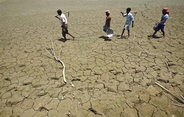 Labourers walk through a parched land of a dried lake on the outskirts of Agartala, capital of Tripura, 23 April 2013. Photo: Jayanta Dey / REUTERS