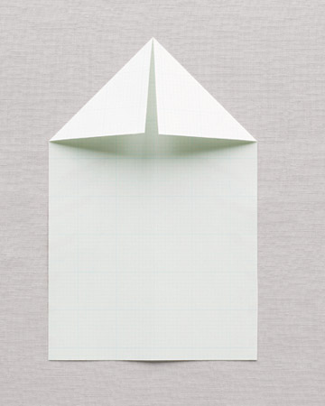 Mark the center crease by folding the long edges together, face in; then unfold the paper and lay it face down, with the airplane pointing up. Fold top corners down to meet the middle crease. Mark the center crease by folding the long edges together, face in; then unfold the paper and lay it face down, with the airplane pointing up. Fold top corners down to meet the middle crease.