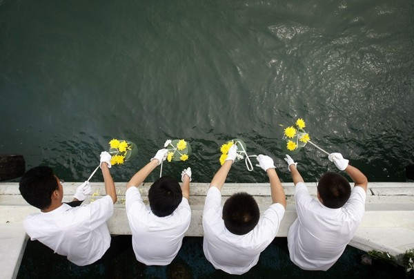 Workers of the Changchun Funeral Home put the ashes of the dead into the sea during a commonweal sea burial in Dalian in northeast China. With prices of graves skyrocketing, the Chinese government is trying to encourage sea burials. Photo: Fang Xinwu / ColorChinaPhoto / AP