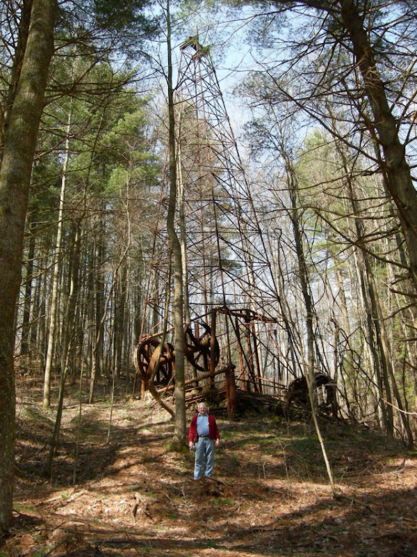 One of the few remaining abandoned oil well derricks in Wetzel County, West Virginia. It stands 85 ft (26 m) and is surrounded by a mature clump of conifers. The boom era for these wells was from the late 1800s until about 1930. This part of northern West Virginia was loaded with them. Bradley Goshen / epod.usra.edu