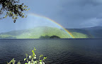 A beautiful rainbow appears in the bright sky after the rain.