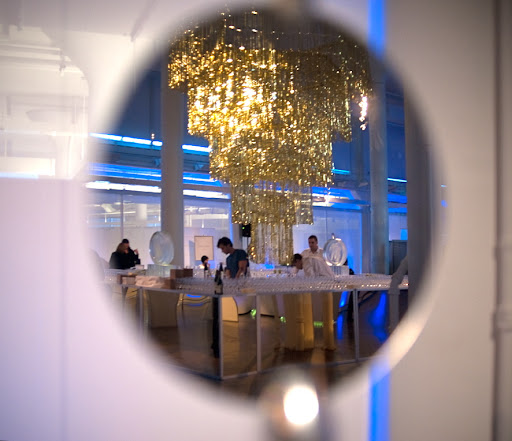 A reflected image of the chandelier, golden bars, and ice sculptures.
