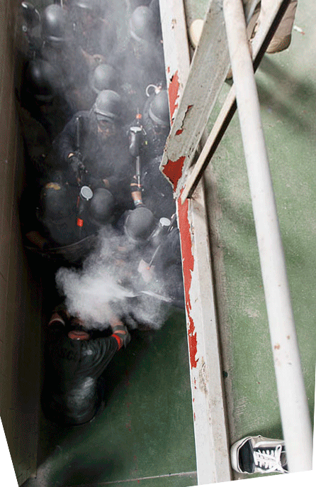 Weber State students Adam Strader and Rachel Taylor try to resist a Federal Bureau of Prisons CERT team during a training scenario at the Mock Prison Riot in Moundsville, West Virginia.