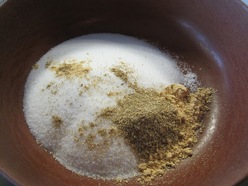 Sugar, baking powder, ginger, and coriander in the bowl ready for more additions.