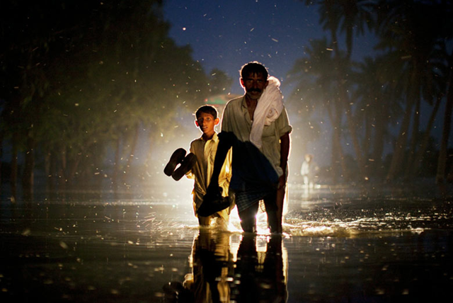 A man and a boy made homeless by the devastating Pakistan floods wade through floodwater in the village of Baseera, in Punjab province, 23 August 2010. Daniel Berehulak / guardian.co.uk