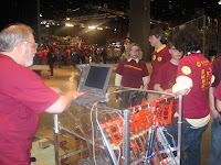 An engineer downloading new code while students discuss strategy