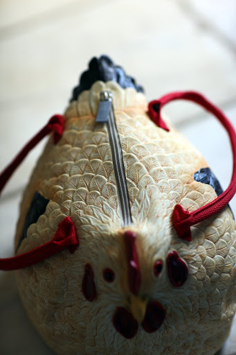 It smells like rubber and has a zipper and two handles.  It must be a chicken hand bag.