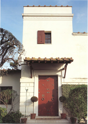 The door is fabulous painted terracotta red and adorned with bronze-studded panels and door-knockers.