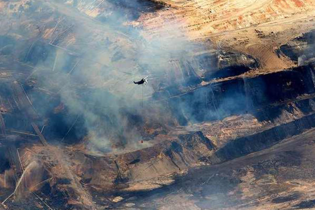A water-bombing helicopter flies over the burning coal mine near Morwell, Australia, on 23 February 2014. Photo: Jason South / The Age
