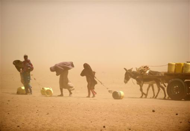 Women and girls, caught in a small sandstorm, fetch water in Wajir in this recently taken handout photo released on 21 July 2011. REUTERS / Jakob Dall / Danish Red Cross / Handout