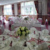 Wedding reception with table decorated with cream roses and chair covers with burgundy sash.jpg