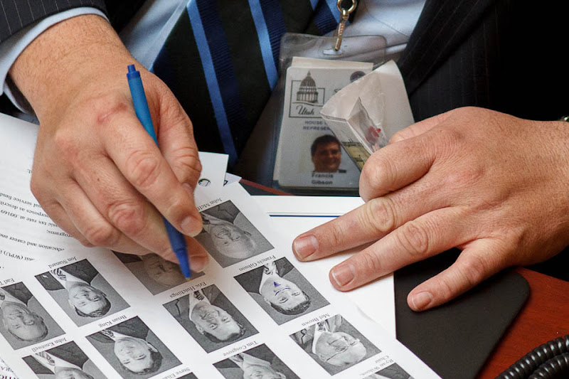 Rep. Francis Gibson draws a doodle on his own photograph in a House roster in the House chamber on the second day of the Utah legislative session in Salt Lake City