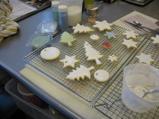 Cookies at various stages of drying and decoration. The royal icing will harden enough that you can touch the surface after an hour or so but it needs to dry overnight before you can decorate with luster dust or package them to give away or mail.