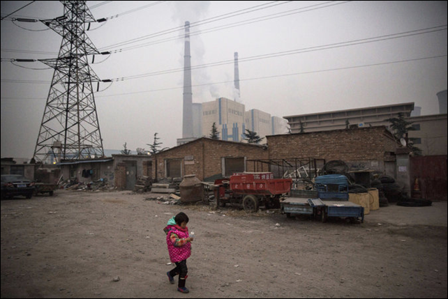 A child walking near her home with a coal-fired power plant in the background in Beijing, China. Photo: Kevin Frayer / Getty Images