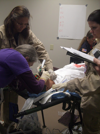 The medical staff member on the left is intubating the mannequin in the intensive care unit of the prep room during the drill. (Photo credit: Jennifer Moore)