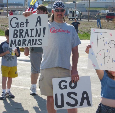 Pro-war counter-protester carries a sign that reads, 'Get a BRAIN! MORANS'. On 23 March 2003, about 350 pro-peace activists took part in a solemn funeral procession to the Boeing missile factory in St. Charles, MO. A hostile crowd of roughly 75, flag waving, pro-war protesters showered the silent peace protesters with insults and violent threats, but they were held back by the police. St. Louis Indymedia Center / shii.org