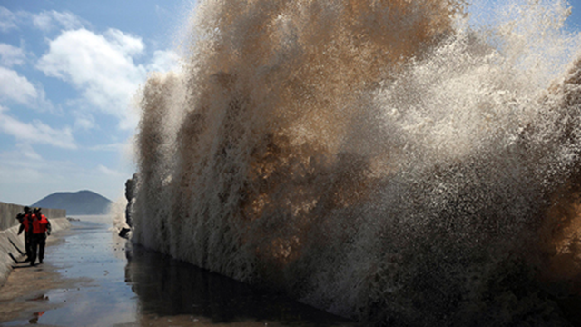 Frontier soldiers look up at the swell against a seawall as Typhoon Soulik approaches in Wenling, Zhejiang province on 12 July 2013. Photo: China Daily / Reuters