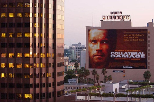A movie billboard advertising Arnold Schwarzenegge...LOS ANGELES, UNITED STATES:  A movie billboard advertising Arnold Schwarzenegger's new film "Collateral Damage" about a bomb blast remains next to a downtown Los Angeles office tower, 12 September 2001. Warner Bros. today announced it was postponing the release of the film "in light of yesterday's tragic events and out of respect for the victims and their families."  Disney also announced it was postponing the release of a film about an attack on US soil called "Big Trouble."   AFP PHOTO/Lucy NICHOLSON (Photo credit should read LUCY NICHOLSON/AFP/Getty Images)