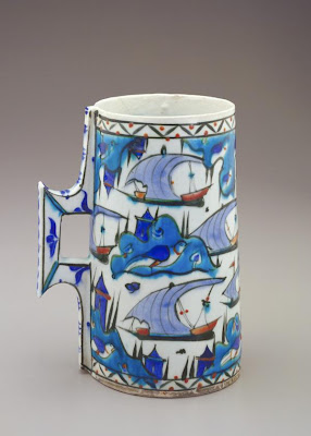 Tankard | Origin:  Iznik,  Turkey | Period: late 16th century  Ottoman period | Details:  In addition to floral, vegetal, and geometric designs, the decoration of Turkish ceramic wares from the city of Iznik occasionally features maritime imagery. The boats on this drinking vessel sail past islands accentuated by small castles, large birds, and pairs of cypress trees. Similar imagery appears in sixteenth century Turkish manuscript illustration, revealing the close connection between the arts during the Ottoman period. | Type: Composite body painted under glaze | Size: H: 21.1  W: 16.4   D: 12.3  cm | Museum Code: F1968.68 | Photograph and description taken from Freer and the Sackler (Smithsonian) Museums.