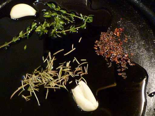 Garlic, herbs, and hot pepper gently infusing oil with flavor.