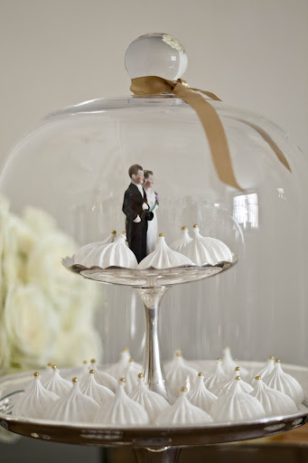 A mini couple standing among dainty meringues at the dessert table. A mini couple standing among dainty meringues at the dessert table.