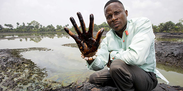 An undated image showing plaintiff Nigerian farmer Eric Dooh showing his hand covered with oil from a creek near Goi, Ogoniland, Nigeria. Photo: Marten Van Dijl / EPA