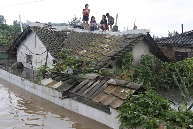 People waited on the roof of a house in Anju, one of the North Korean cities hardest hit by flooding, 30 July 2012. Kim Kwang Hyon / Associated press