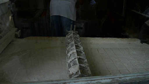 To make the beignets, this machine flattens the yeast dough and stamps out squares.