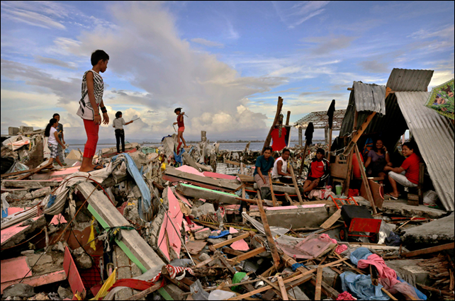 Residents gather amongst the devastation in the aftermath of Typhoon Haiyan on 13 November 2013 in Tacloban, Leyte, Philippines. Typhoon Haiyan, packing maximum sustained winds of 195 mph (315 kph), slammed into the southern Philippines and left a trail of destruction in multiple provinces, forcing hundreds of thousands to evacuate and making travel by air and land to hard-hit provinces difficult. Photo: Kevin Frayer / Getty Images