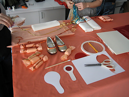 One of our work stations. The coral, red, and peach work station, apparently. That's me and our intern Stephanie working on the ring pillows.