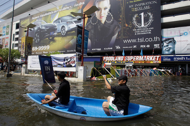 Thai men use a boat to navigate through floodwaters outside a shopping mall in Bangkok's Laksi district on 1 November 2011. Aaron Favila / Associated Press