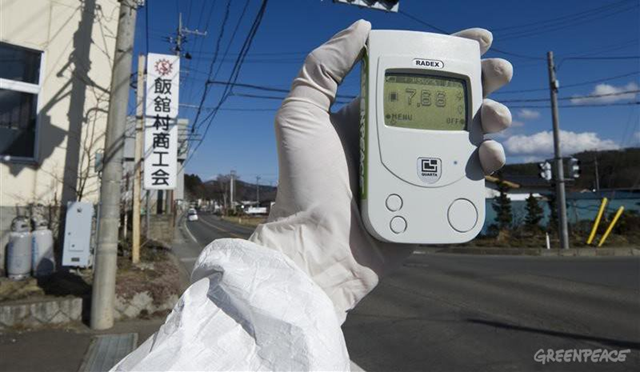 A Greenpeace team member holds a Geiger counter displaying radiation levels of 7.66 micro Sievert per hour Iitate village, 40km northwest of the crisis-stricken Fukushima Daiichi nuclear plant, and 20km beyond the official evacuation zone, 27 March 2011. &copy; Christian &Aring;slund / Greenpeace