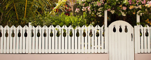 A picket fence with pineapple carvings.