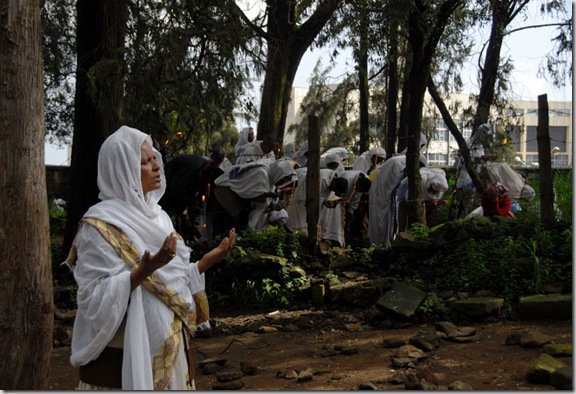 A woman prays by herself as others light candles in prayer on St. George's Day at St. George's Church in Addis Ababa on August 29, 2007.