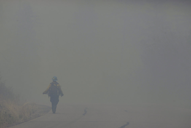 A firefighter walks through heavy smoke from the Las Conchas fire near Los Alamos, N.M., Wednesday, June 29, 2011. As crews fight to keep the wildfire from reaching the country's premier nuclear-weapons laboratory and the surrounding community, scientists are busy sampling the air for chemicals and radiological materials. AP Photo / Jae C. Hong