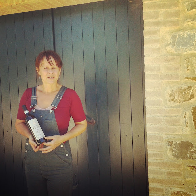 A vineyard worker holding a bottle of Brunello di Montalcino