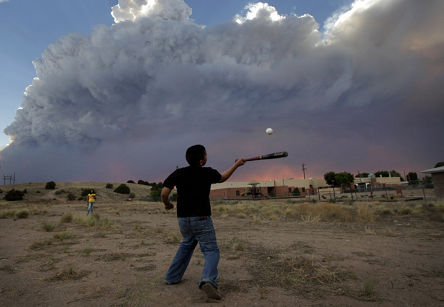 Alex Lopez, center, plays baseball with his sister Sugey while smoke generated by the Las Conchas fire covers the sky in Espanola, N.M., Wednesday, June 29, 2011. As crews fight to keep the wildfire from reaching the country's premier nuclear-weapons laboratory and the surrounding community, scientists are busy sampling the air for chemicals and radiological materials. AP Photo / Jae C. Hong