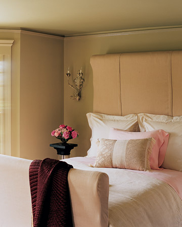 This bed frame is encased in thick bump padding, then in fine-linen slipcovers that are stitched together into a simple dressmaker shape that gracefully envelops the frame of the bed. Pink linens accentuate the pink in the wall color.