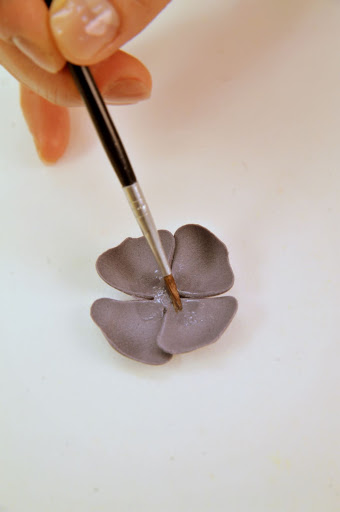 Here, she preps the petals before attaching them to the bud.