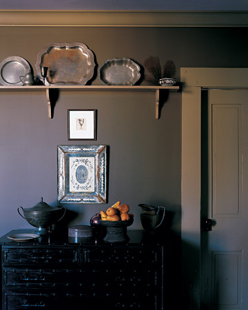 The silver pieces and Venetian mirrored frame pair gracefully with the dark wall. (marthastewart.com)