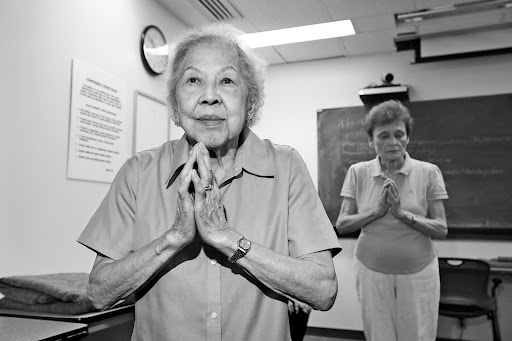 Margaret King, age 97, stands with her hands in prayer position in yoga class.