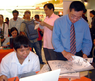 Red Fox Animation Studio Manager Mr. Bernard Yeo inspects the designs of Jerson.