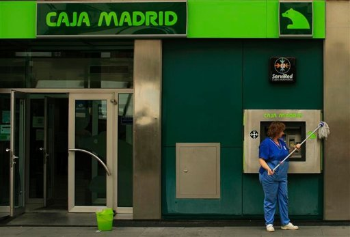 A cleaner cleans the facade of a Bankia-Caja Madrid bank branch in the Andalusian capital of Seville, 25 June 2012. Spain formally requested European aid for its banks on Monday but did not specify how much money it will seek to recapitalize the indebted lenders. Marcelo del Pozo / REUTERS