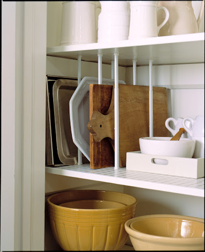 Curtain tensions rods fitted in between shelves in a pantry create vertical storage for platters, trays and cutting boards.