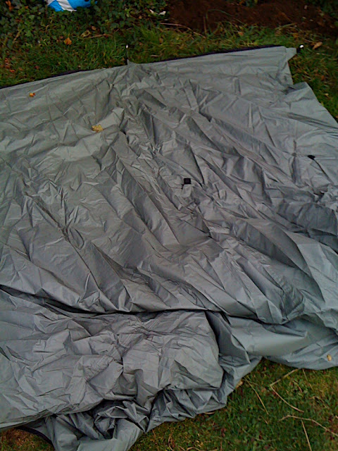 The tent laid out on the ground. The useful "pitching guide arrived with the order by email as a word document (to save the environment): very simple but valuableinstructions. 1. Peg out the grounsheet (black) first, but loosely. 2. Insert your uprights - can be paddles if canoeing, or walking poles or just sticks from your campsite.