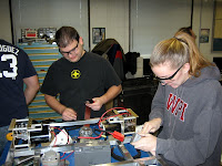 A mentor assists a student with mounting the battery on our frame